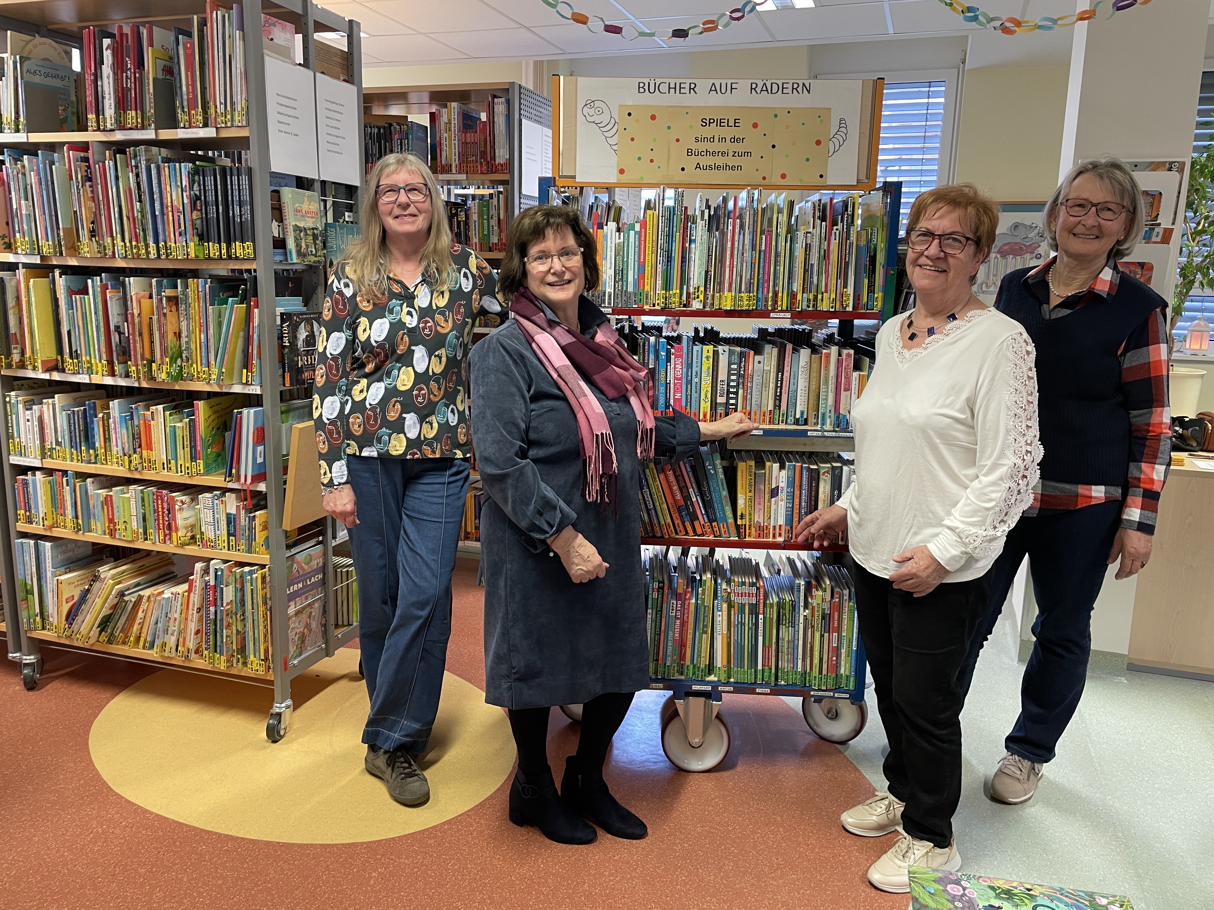 Ehrenamtliche Mitarbeiterinnen mit einem der Bücherwagen